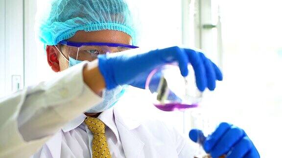 一个男性科学家在实验室用吸管填充试管的特写