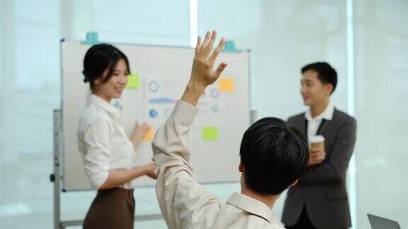 在一个现代化的办公室里年轻的商人在商务研讨会上举手提问