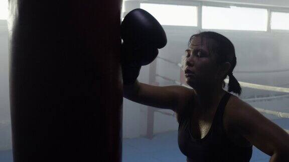 精疲力竭的女性自由搏击运动员休息期间密集的锻炼与拳击袋