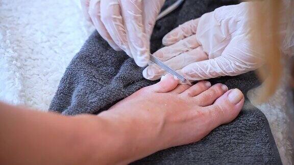 专业的足科医生戴着白手套用硬件锉打磨脚趾甲并塑造形状在美容院进行治疗性足疗足疗程序概念