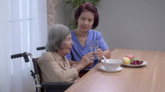 照顾者给亚洲老妇人喂汤