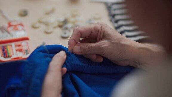 特写退休亚洲妇女缝纫她的衣服手工