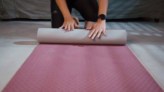 近距离卷起瑜伽垫在家里的客厅锻炼