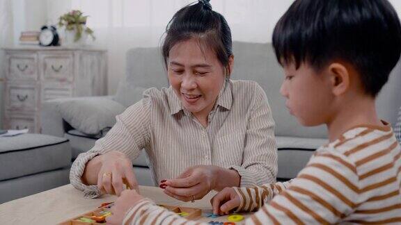 4K亚洲单身妈妈在假期和儿子玩棋盘游戏这是他和儿子在假期做的一项活动男孩非常决心要玩