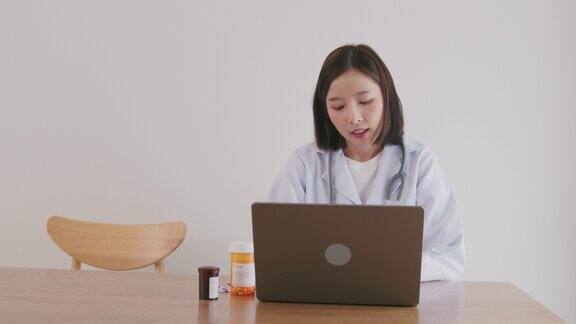 亚洲女医生正在用笔记本电脑与病人进行视频通话远程医疗