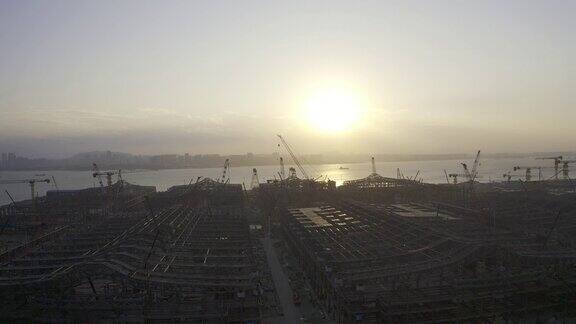 一个大型建筑工地在日落前的背光航拍视频一个巨大的太阳在天空中