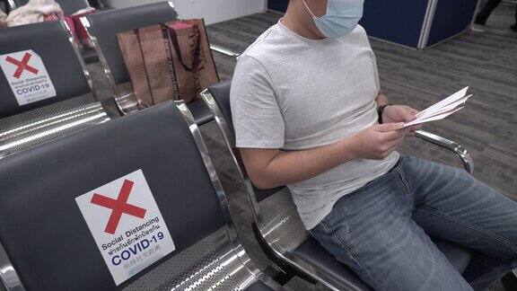 亚洲男人在机场坐着保持社交距离这是新常态