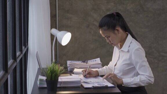 年轻的会计用图纸工作一个亚洲女人在办公室工作时使用笔记本电脑的特写