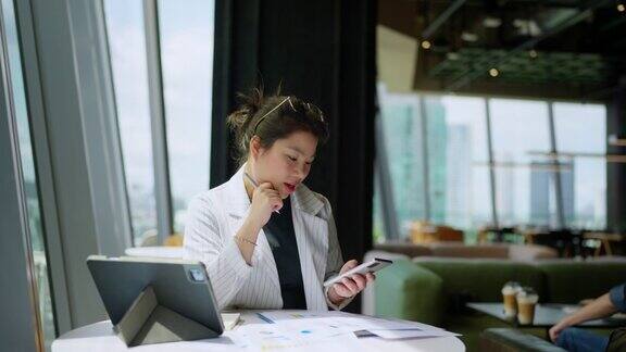 放松休闲有吸引力的聪明的亚洲女性自由企业家微笑享受与智能手机和笔记本电脑在咖啡馆与模糊的城市商业观点数字游牧民休闲想法