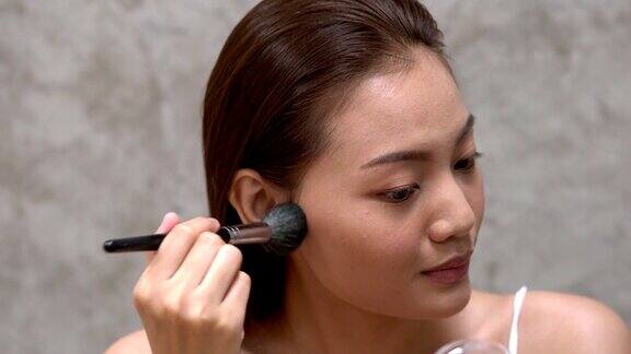 美丽的亚洲女人使用化妆刷