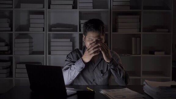 亚洲男性商人在办公室用财务文件和台式电脑工作到很晚加班的年轻人工薪族概念4k