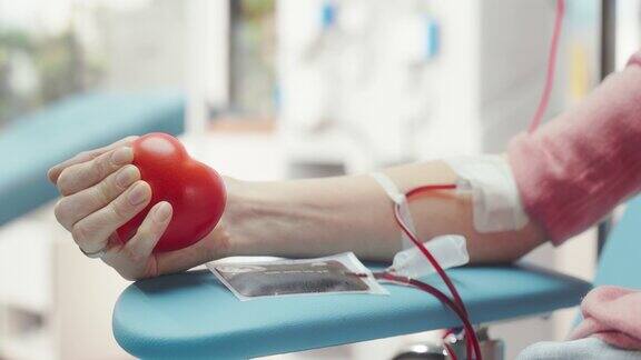 女性献血者的手的特写镜头白人妇女挤压心形红球将血液通过管道泵入袋中为烧伤病人捐款