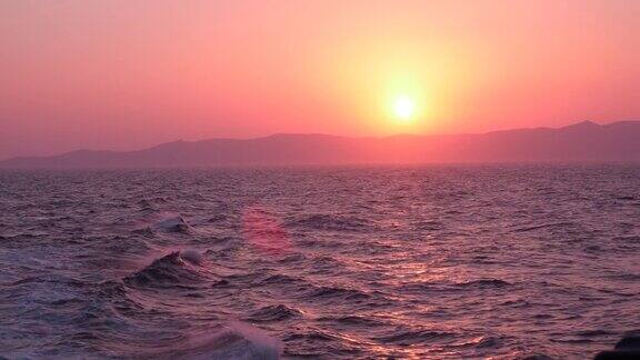 地中海上美丽的粉红色日落海浪与背景中的山脉相撞