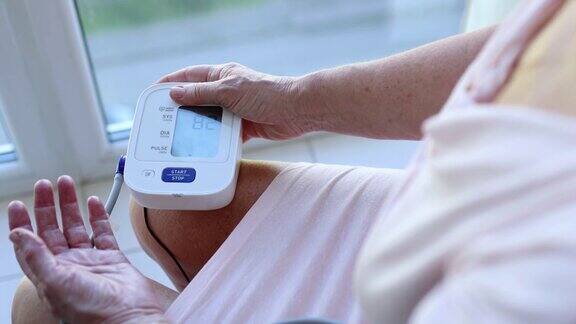 成熟的老年妇女用近距离血压监测仪测量血压