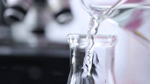 科学家化学家倒水从试管到烧瓶在实验室近距离4k电影慢动作