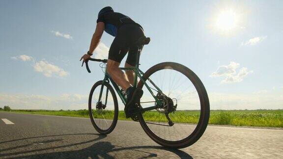 一个骑自行车的运动员正站在踏板上高速发展骑自行车训练从背后开枪太阳在背后4k