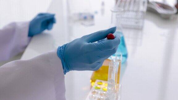 近距离观察实验室里科学家或技术人员的手在玻璃管里测试化学液体理科教室实验室里的老师在桌子上展示溶液液体在实验室里用蓝手套测试样品