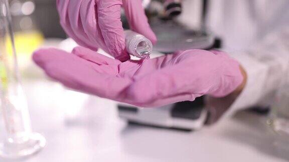 戴着防护手套的科学家化学家在实验室特写4k电影慢镜头中将液态金属倒入手上