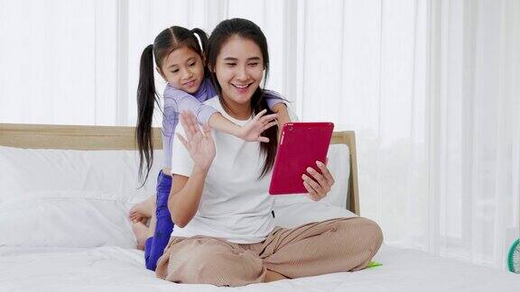 快乐的妈妈和小女儿用数字平板电脑玩科技视频通话的乐趣