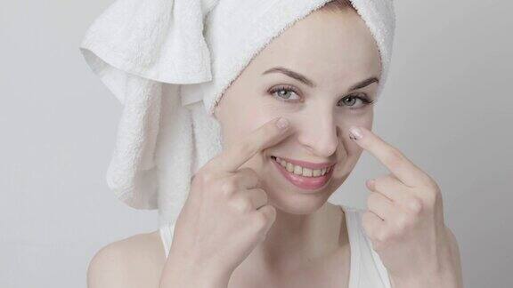 华丽的女人用毛巾在她的头应用净化黑炭面膜在她的脸