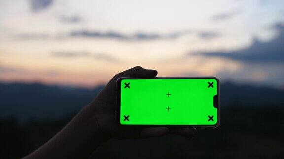 男人拿着智能手机的绿色屏幕与自然戏剧性的天空为背景色度键景观模式