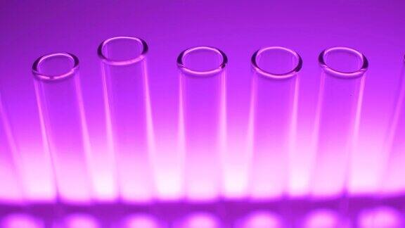 实验室里用紫光和紫光照射的玻璃试管近距离观看4K视频