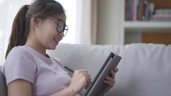 年轻女性在家里的客厅里放松使用数码平板电脑