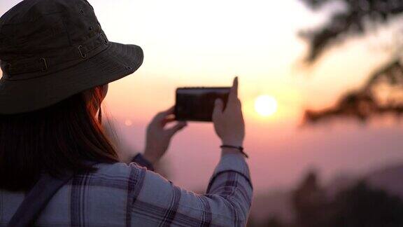 女旅行者在山上一个美丽的地方拍摄日落