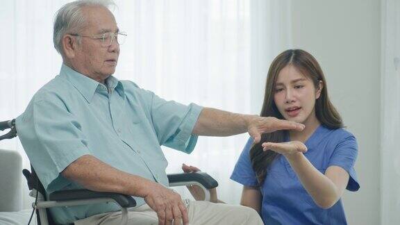 家庭保健东南亚老年人护理护士、理疗师在护理中帮助残疾老年病人做运动