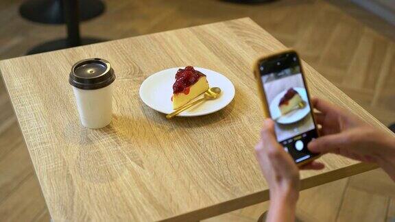 4K亚洲女人用手机拍摄咖啡桌上的芝士蛋糕