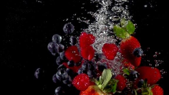 超级慢动作的草莓覆盆子沼泽越桔蓝莓落入飞溅的水鲜榨果汁烹饪概念拍摄于高速影院摄像机4k1000fps