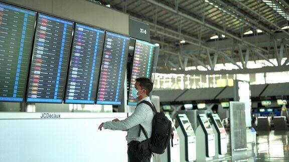 日落时分一名亚洲男子走进候机楼在机场门口查看航班时刻表