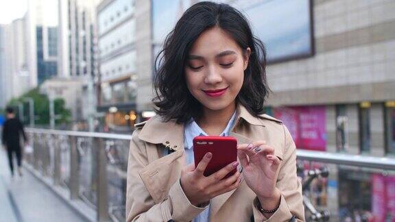 一个年轻漂亮的亚洲女人在城市里使用手机