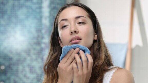 年轻迷人的女人用毛巾洗脸