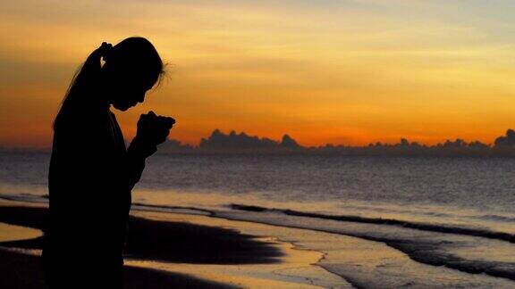 女人祈祷在美丽的日落背景
