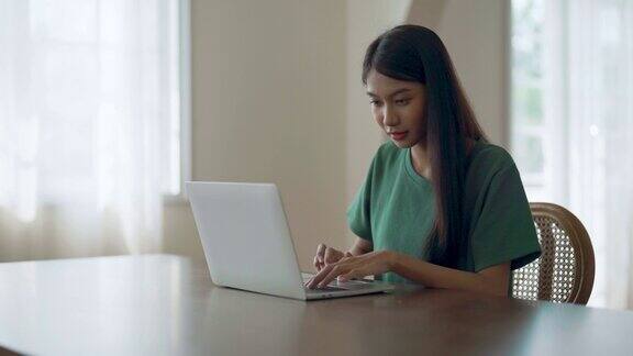 在家工作的年轻亚洲女性女性在家桌上使用电脑笔记本电脑