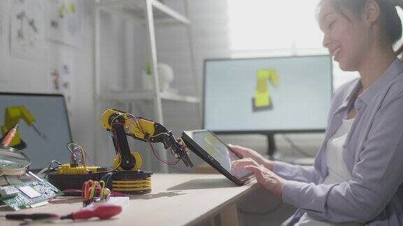 女工程师正在他的车间里研究创新技术机械机器人手臂她用数字平板电脑用手控制机器人手臂