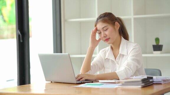 一位年轻的女商人看起来很紧张因为她在电脑前工作亚洲女性因为整天在笔记本上工作而头痛