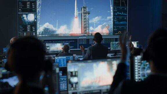 任务控制中心的一群人见证了火箭发射的成功飞行控制人员坐在电脑显示器前监控机组人员的任务队员起立鼓掌