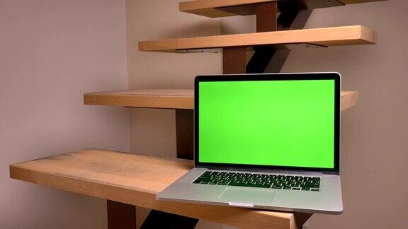 笔记本电脑的特写镜头绿色的屏幕躺在室内的办公室楼梯上
