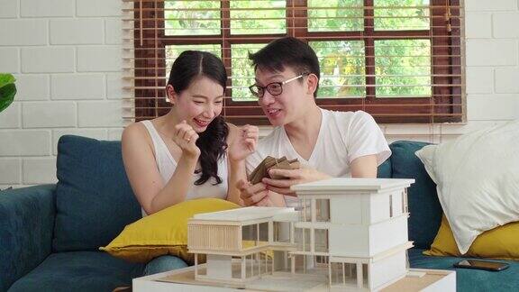 一对亚洲夫妇正在为他们的新房子项目审查房子模型选择墙壁颜色规划室内装饰