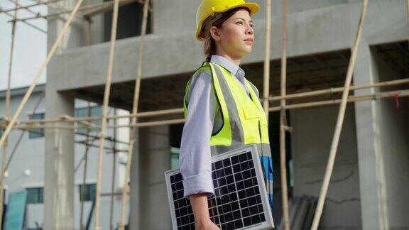 亚洲女工程师拿着一块太阳能电池板在建设可持续资源村项目发展项目走过工地利用可持续资源