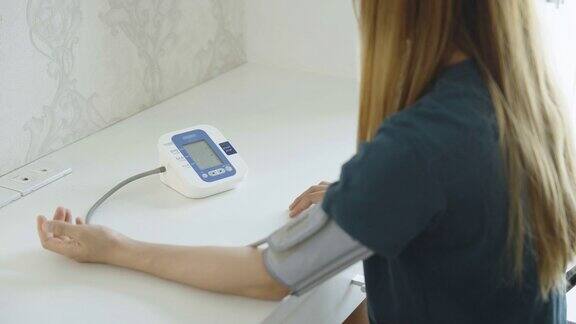 年轻的亚洲妇女在家里测量她的血压计