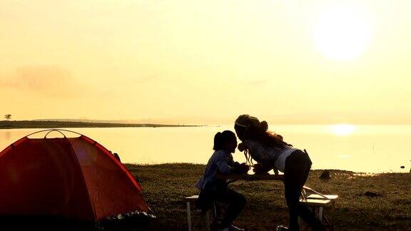 小女孩和她的母亲在帐篷附近放松露营