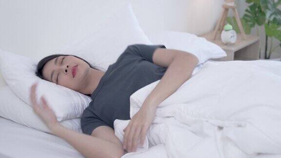 年轻美丽的亚洲女人在早上的床上快乐地睡觉