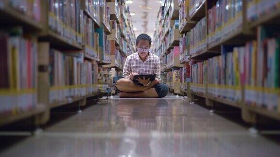 小女孩在图书馆的书架上阅读电子书
