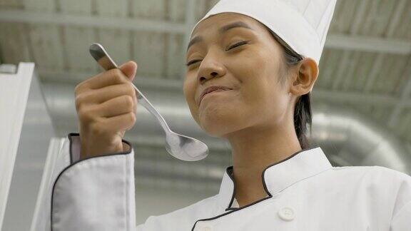 快乐的年轻女厨师在工业厨房准备和品尝一顿饭