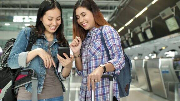 两名女子在候机楼用智能手机检查航班
