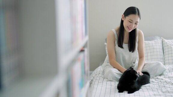 4K年轻的亚洲女子早上醒来后在床上玩黑猫