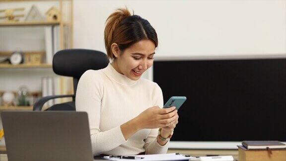 美丽的亚洲女人在工作间隙玩手机她是一家创业公司的市场经理女性领导主管ceo女性领导力